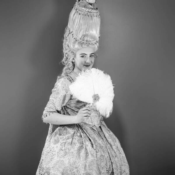 Alannah Blumstein on black and white background, with full Marie Antoinette dress, waving fan