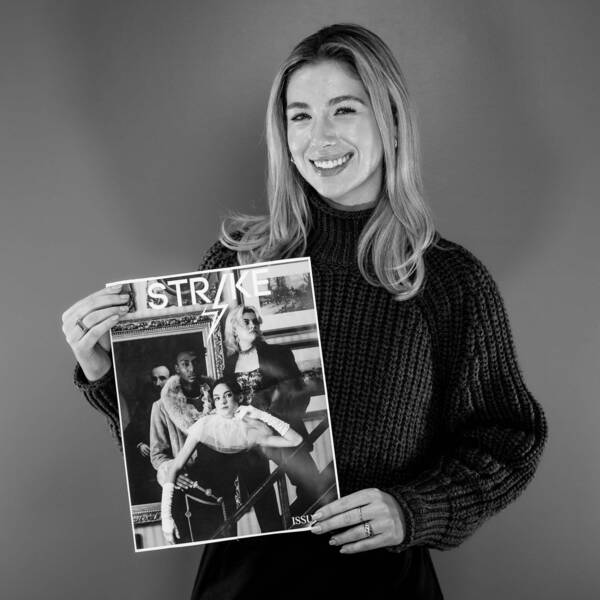 Gracie Simoncic posing with smile, holding up a copy of Strike magazine, wearing a dark sweater