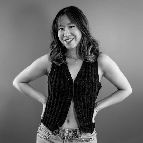 Felicity Wong black and white image smiling with hands on hips, wearing jeans and a black vest