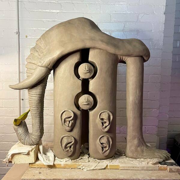 Sculpture in progress-clay work with a banana, a human leg, an elephant trunk, and ears