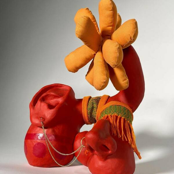 Red and orange sculpture with orange crochet and earrings, ears, and nose