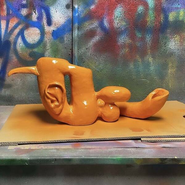 orange sculpture with an ear and beak